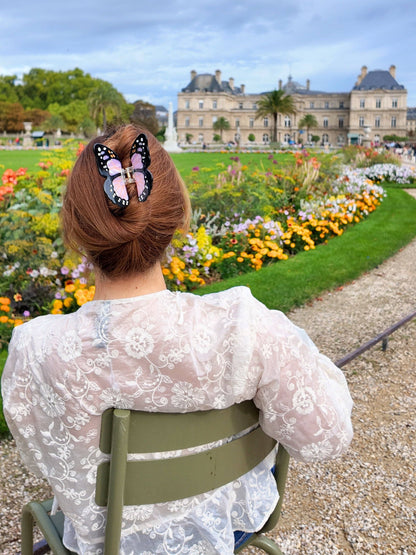 Lilac butterfly clip in a bun, woman in a lace top in a formal garden