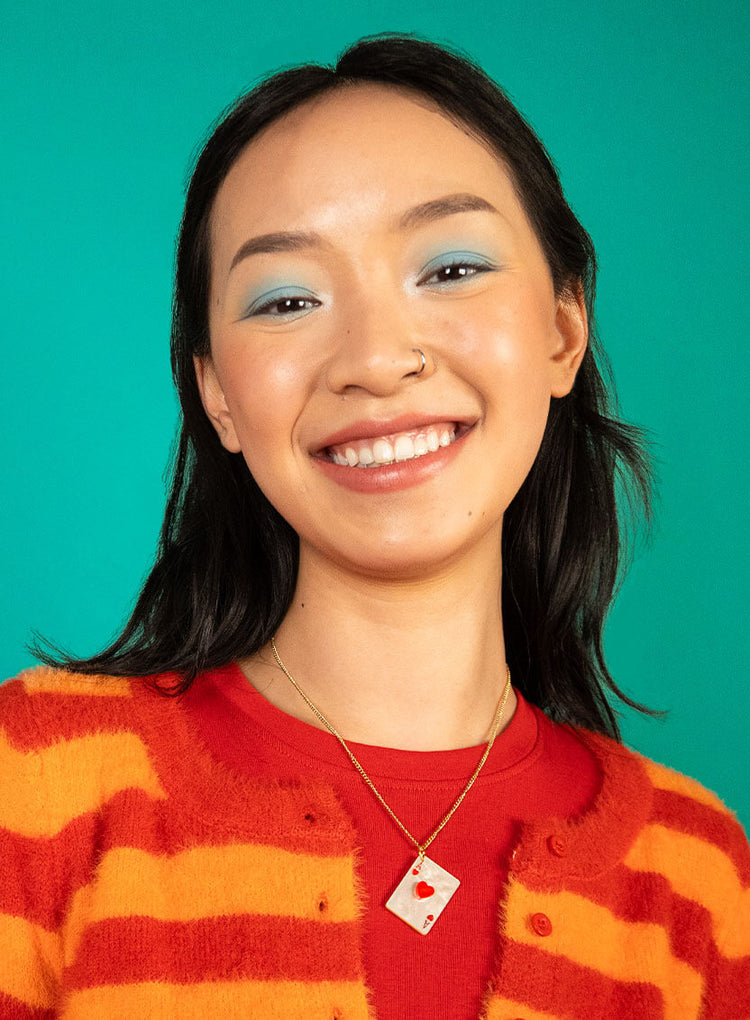 Smiling woman in a striped top wearing the ace of hearts pendant