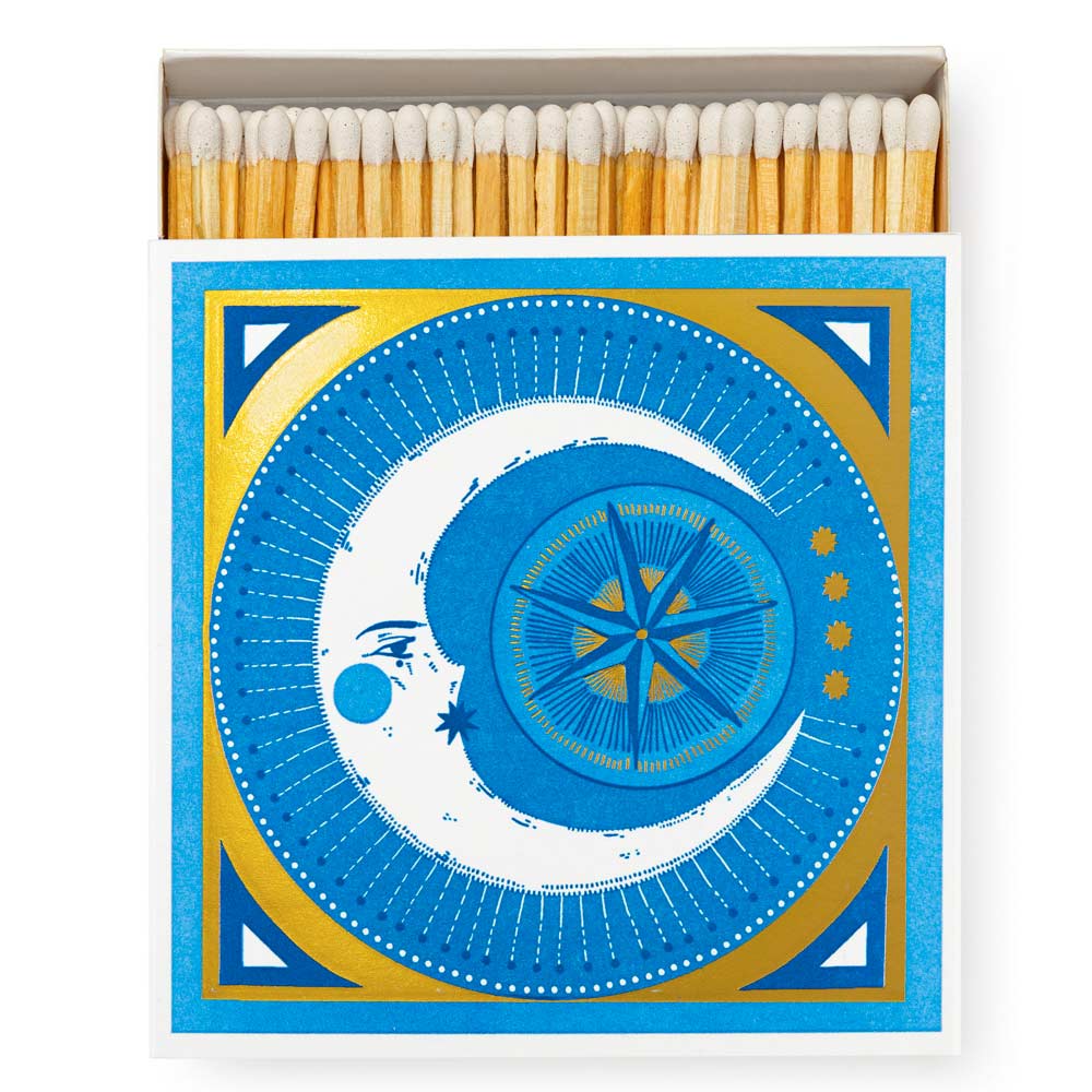 Square box of luxury matches with a blue crescent moon face and a compass on gold