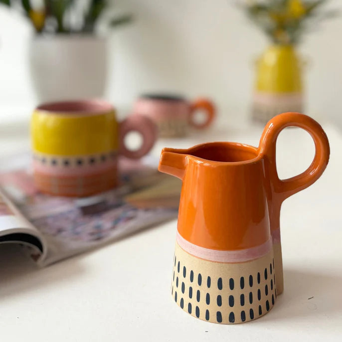 Bloc orange jug on a table beside a yellow mug