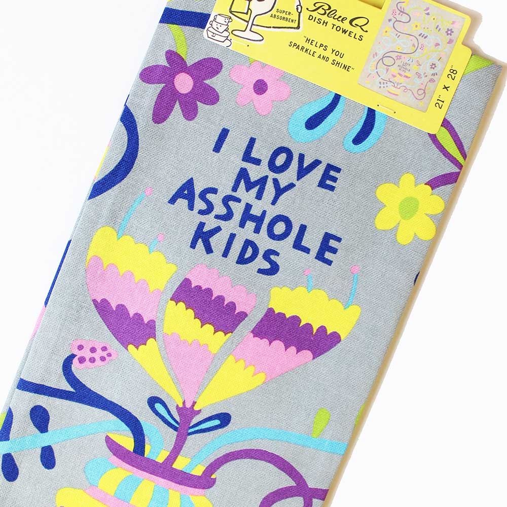 Blue Q tea towel, folded: bright flowers and the words 'I love my asshole kids'