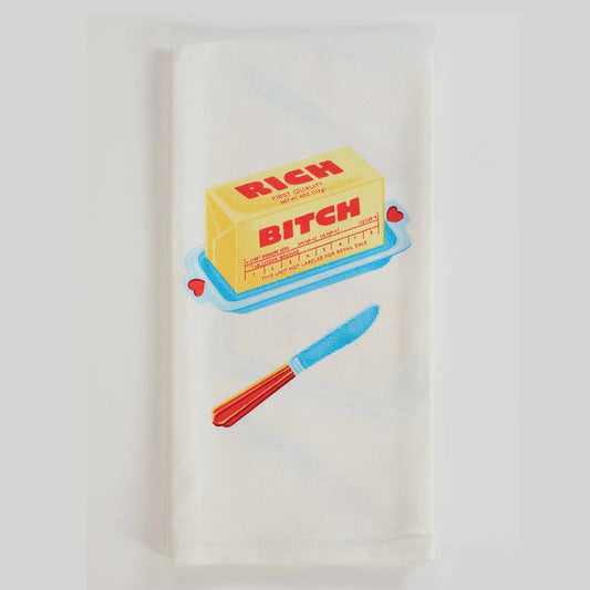 Blue Q tea towel, folded: a block of butter labelled 'Rich bitch' with a butter knife