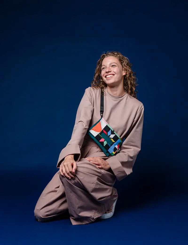 Woman wearing the Playground crossbody bag on a blue background