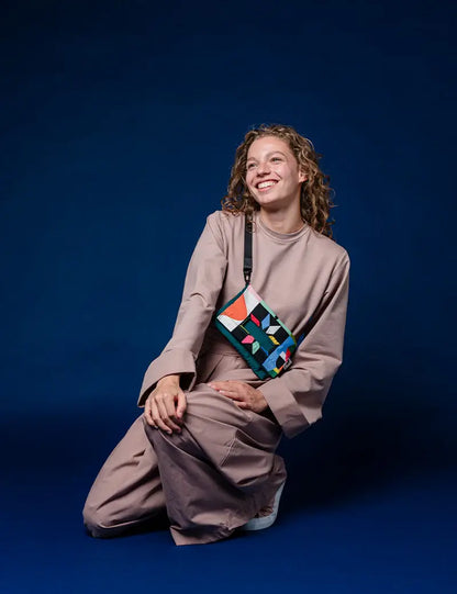 Woman wearing the Playground crossbody bag on a blue background