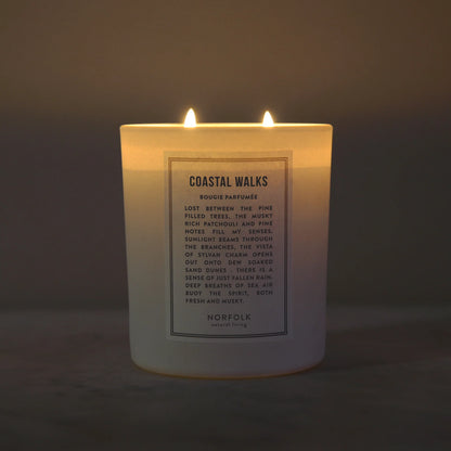 Coastal Walks candle lit, with two wicks glowing in a dim room