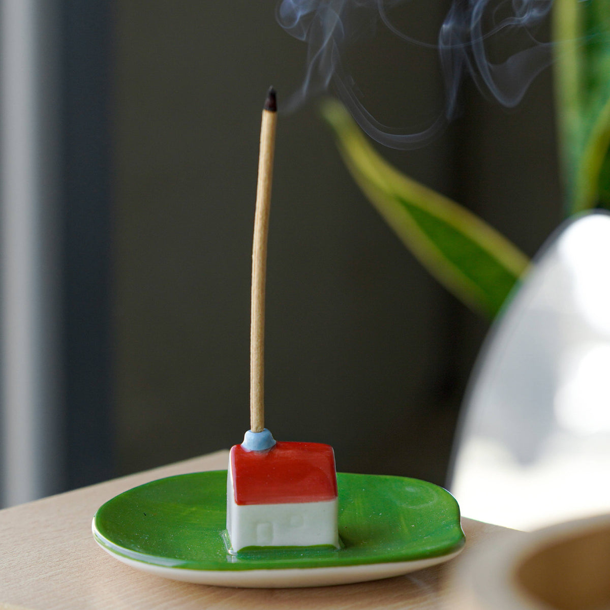 Green incense dish with a red-roofed house holding a burning stick