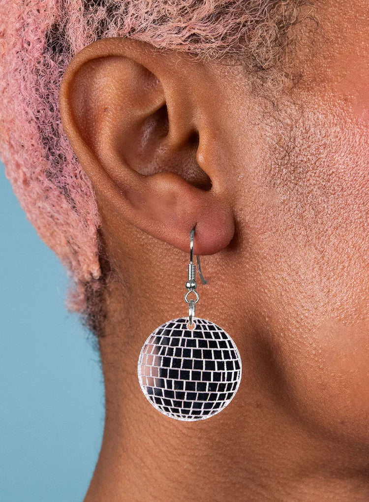 Disco ball earring worn on a person with pink hair