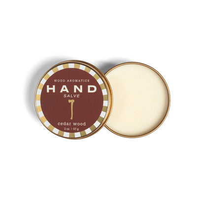 Open tin of cedar wood hand salve beside its lid