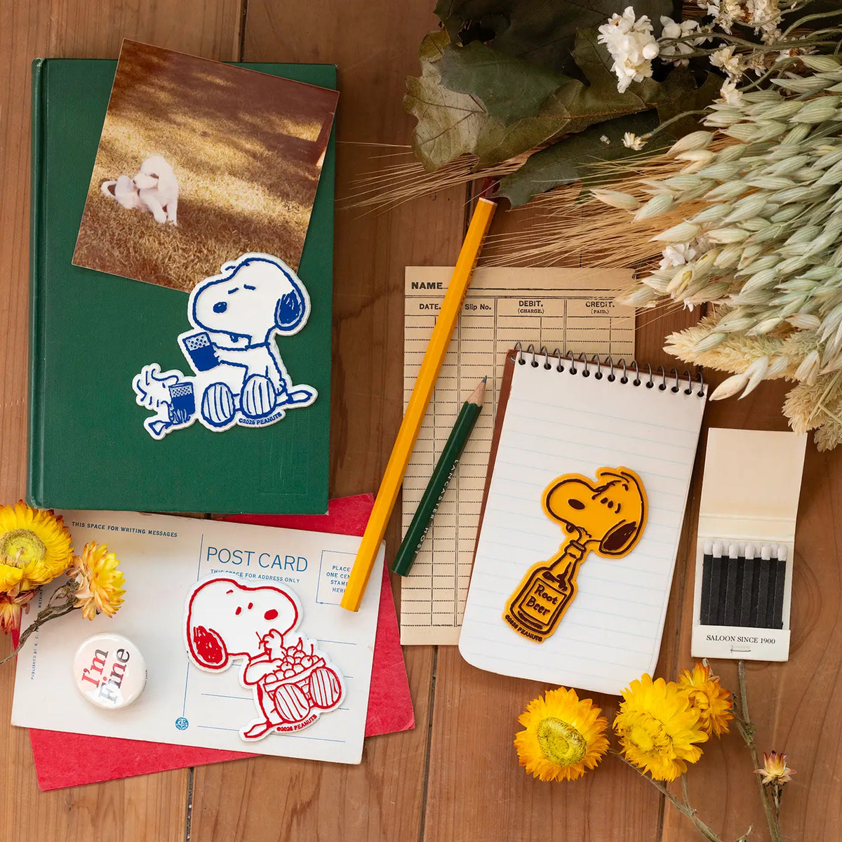 Snoopy magnets including the cheers magnet on a desk with a notebook