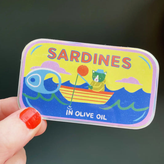 Naomi Wilkinson sticker of a tin of sardines in olive oil with a frog in a boat, held in a hand