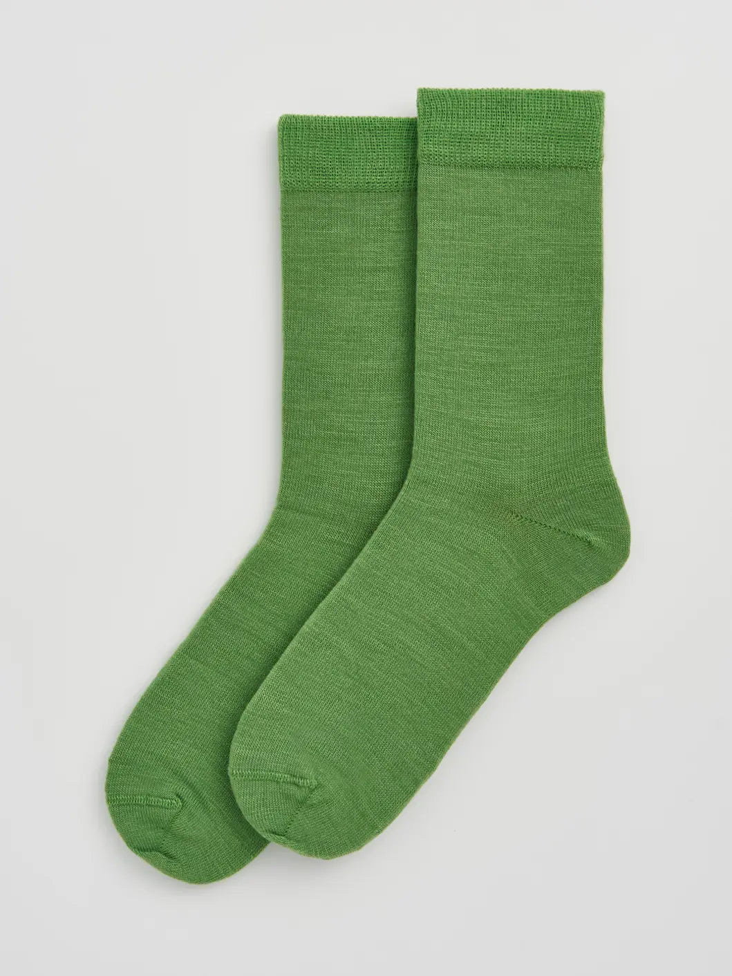 Pair of grass green calf-length merino socks laid flat