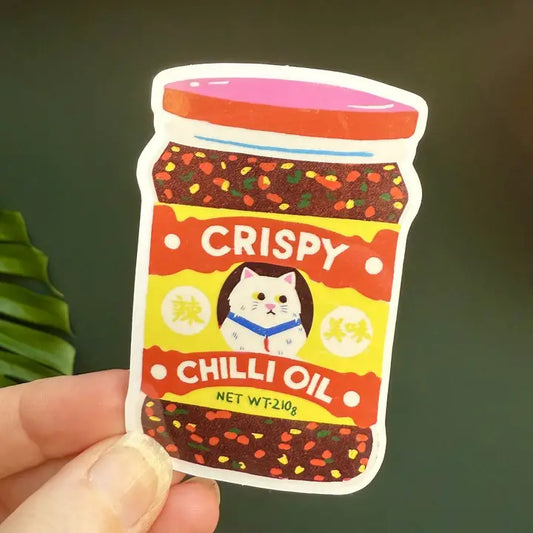 Naomi Wilkinson sticker of a jar of crispy chilli oil with a cat on the label, held in a hand