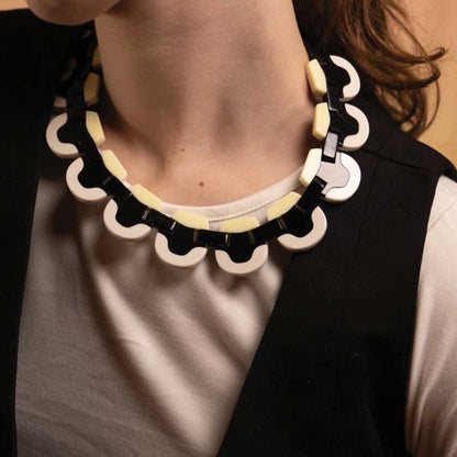 Woman wearing a black and cream wave-edged acrylic necklace