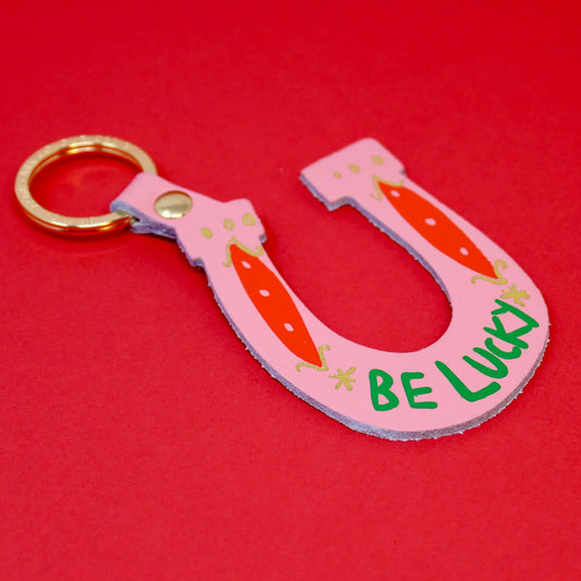 Ark pink leather horseshoe key ring with 'Be lucky' in green