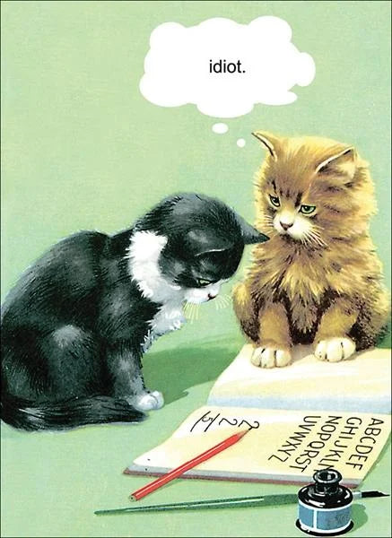 Kiss Me Kwik card: a black and white kitten and a ginger kitten over a spelling book, with a thought bubble saying 'idiot.'