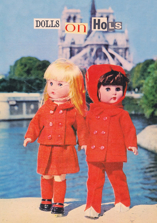 Kiss Me Kwik card: two dolls in red coats in front of Notre-Dame, with collage letters reading 'Dolls on hols'