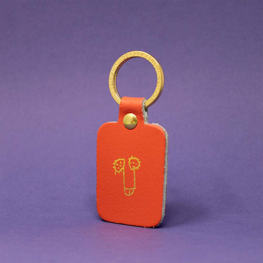 Coral leather key fob with a gold cartoon penis