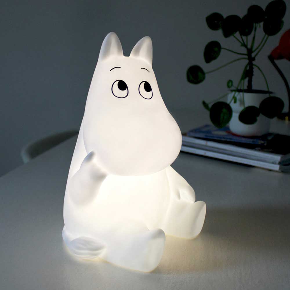 Sitting Moomin lamp lit up on a table beside a plant