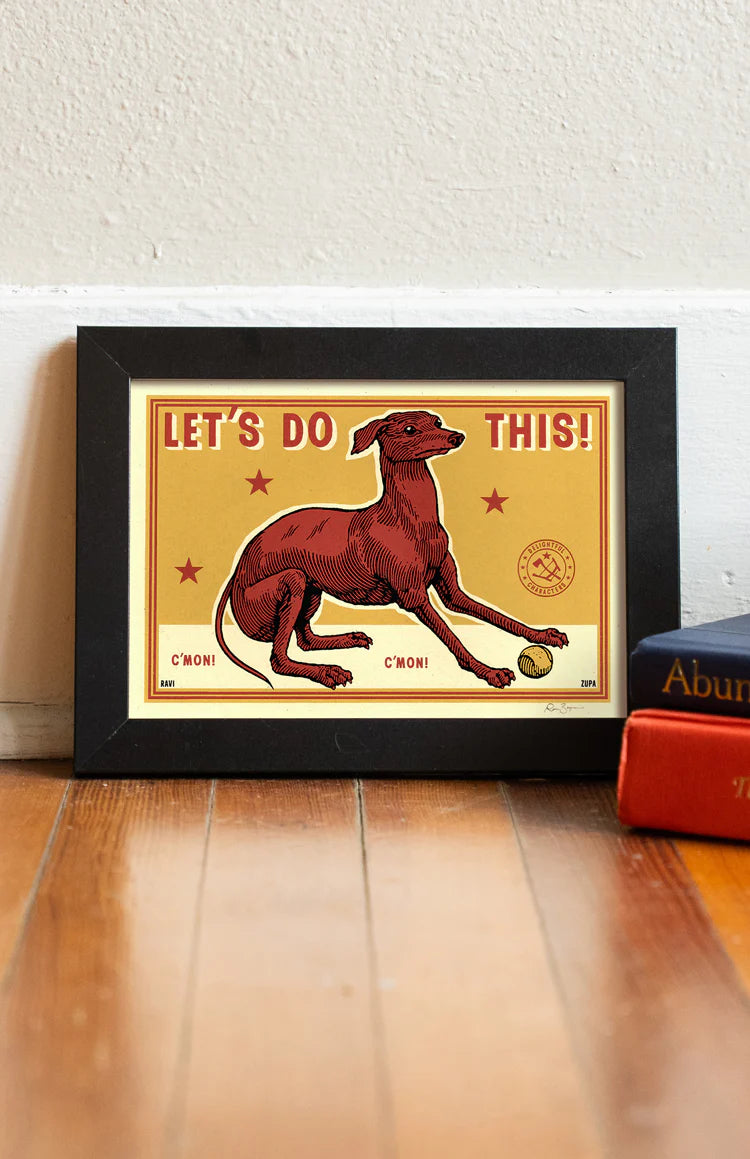 Let's Do This print in a black frame on a wooden floor
