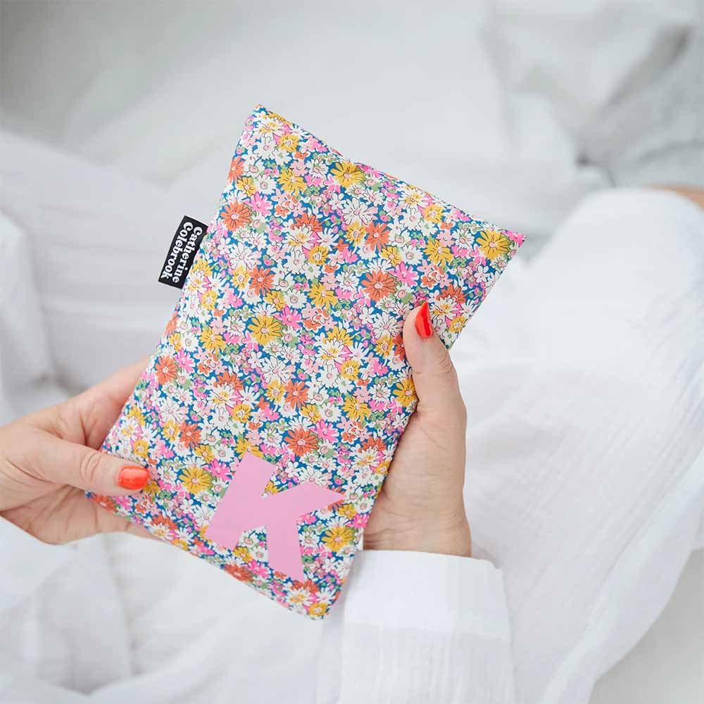 Hands holding a Liberty floral print hot water bottle cover with a pink star