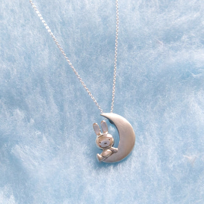 Miffy sitting on a crescent moon pendant on blue fur