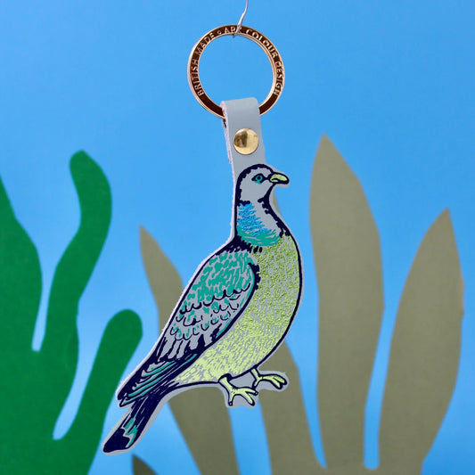 Ark lilac grey feral pigeon leather key fob, against a blue background with plants