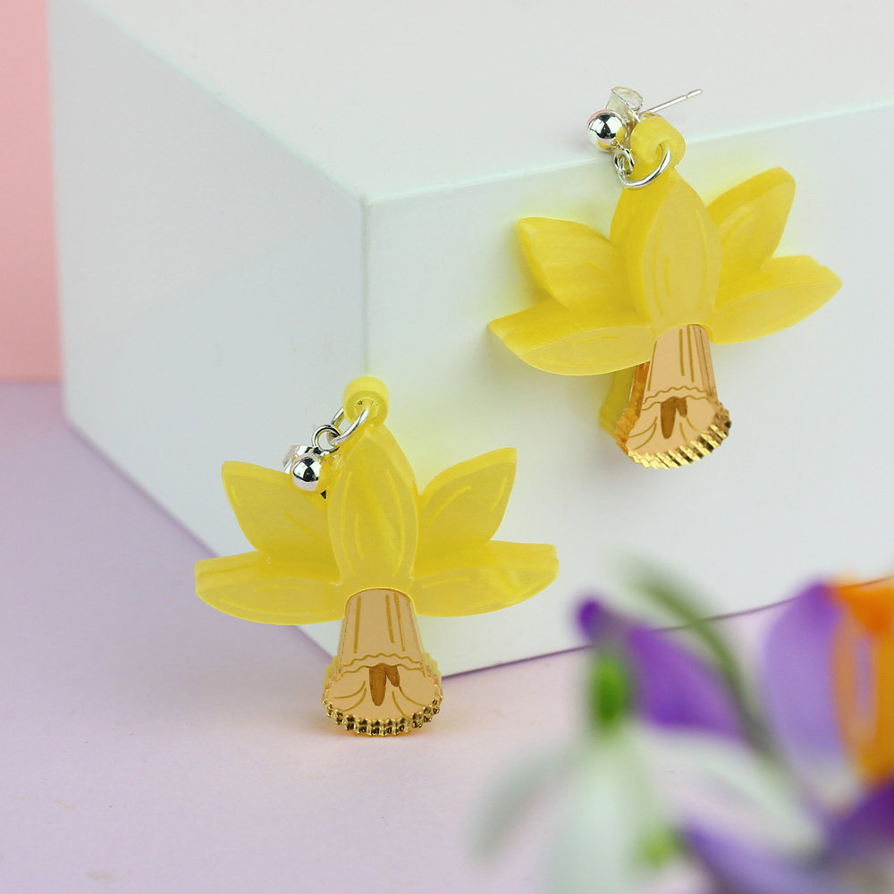 Daffodil earrings hanging off the edge of a white box