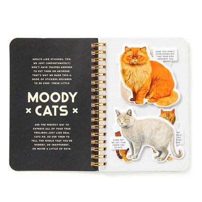 Moody Cats sticker book open at the title page, with orange and grey cat stickers and speech-bubble captions