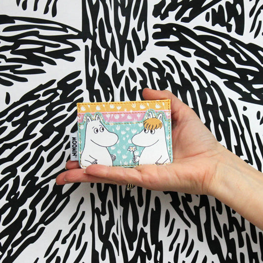 Hand holding a pastel floral card holder with Moomintroll and Snorkmaiden