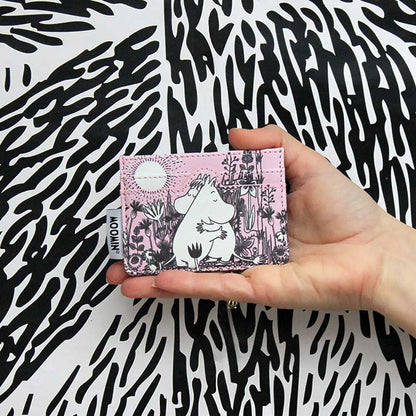 Hand holding the pink Moomin Love card holder against a black and white pattern