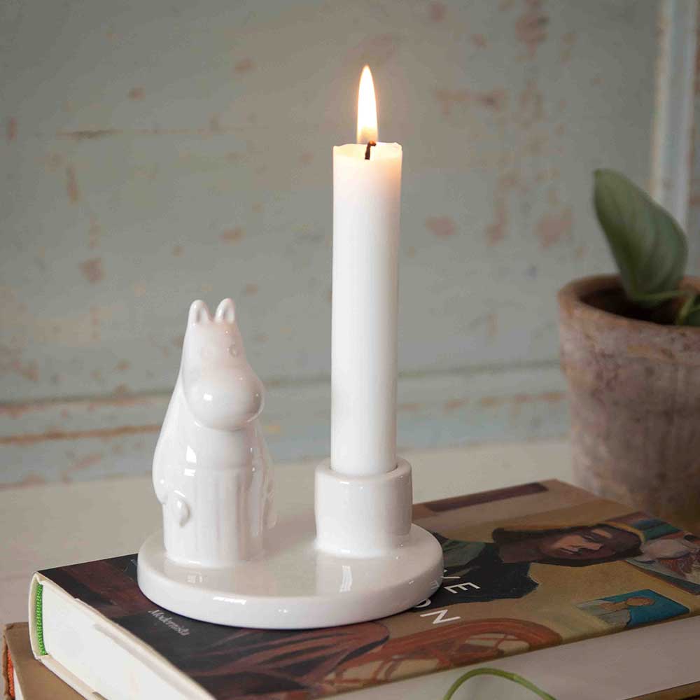 Moominmamma candle holder with a lit candle on books
