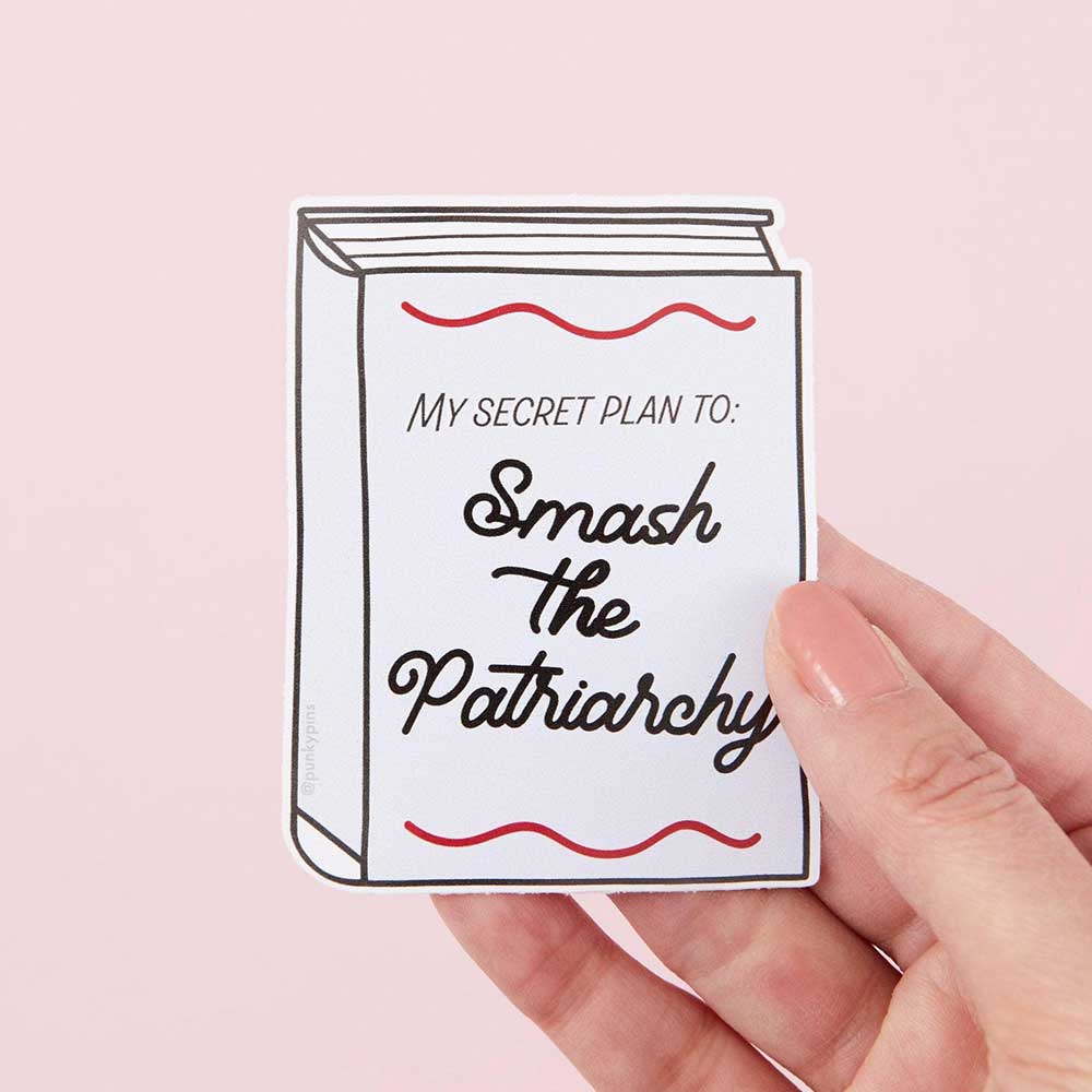 Hand holding a book-shaped sticker: My secret plan to: smash the patriarchy