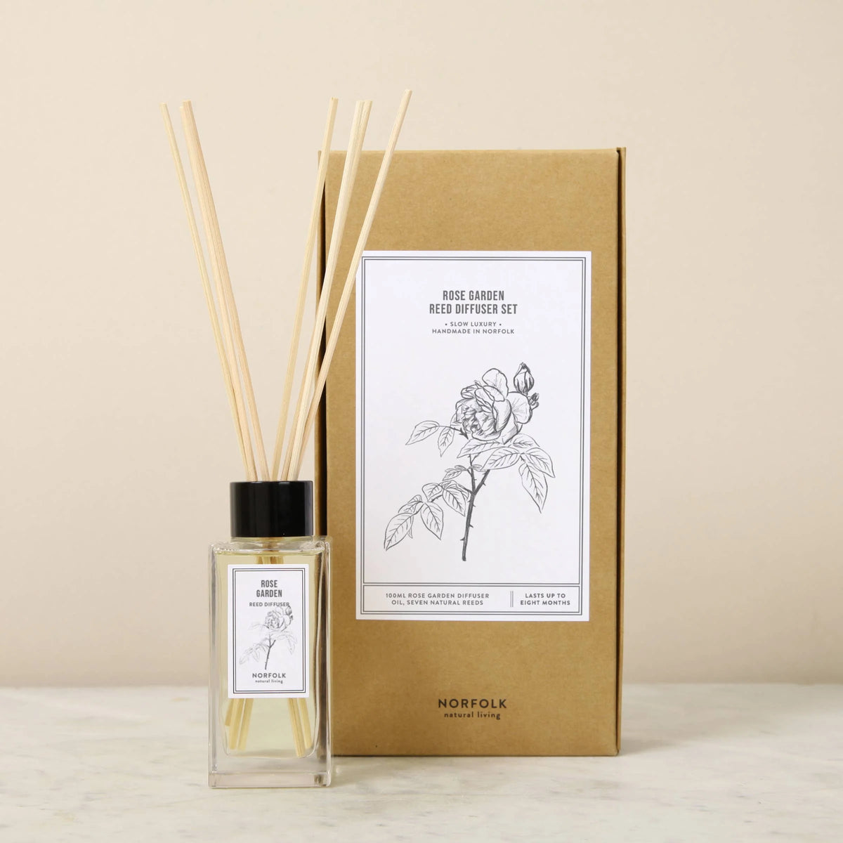 Rose Garden reed diffuser set with reeds in a glass bottle beside its kraft box
