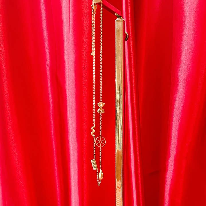 Pasta shape necklace hanging against a red curtain