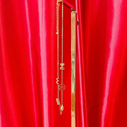 Pasta shape necklace hanging against a red curtain