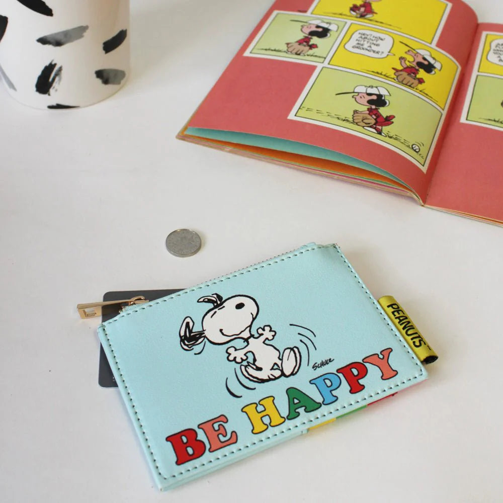 Be Happy zip purse on a table beside a Peanuts comic book