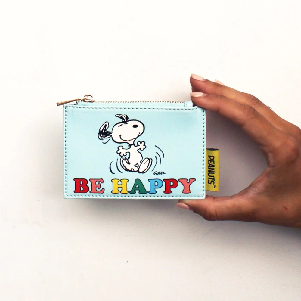 Hand holding the pale blue Peanuts zip purse with dancing Snoopy and 'Be happy' in rainbow letters