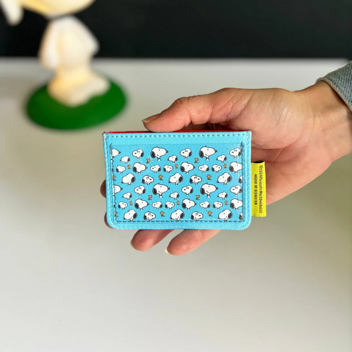 Back of the Peanuts bus card holder: turquoise with an all-over pattern of small Snoopy faces
