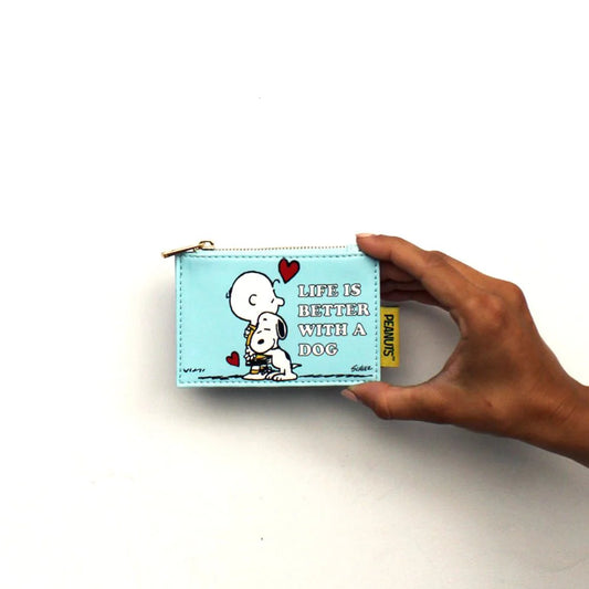 Hand holding the pale blue Peanuts purse with Charlie Brown hugging Snoopy and 'Life is better with a dog'