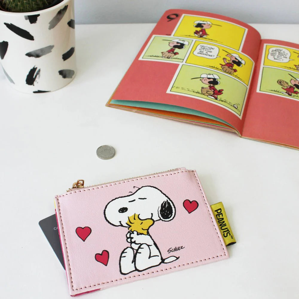 Pink Peanuts Love zip purse with Snoopy hugging Woodstock and red hearts, beside a comic book
