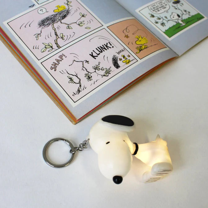 Snoopy light-up key ring glowing beside a Peanuts comic