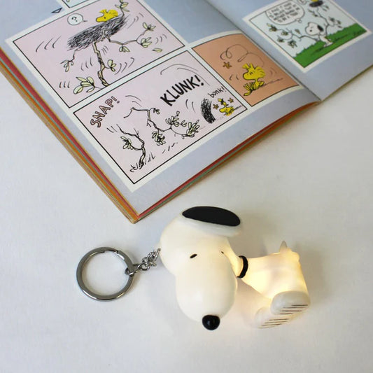 Snoopy light-up key ring glowing beside a Peanuts comic