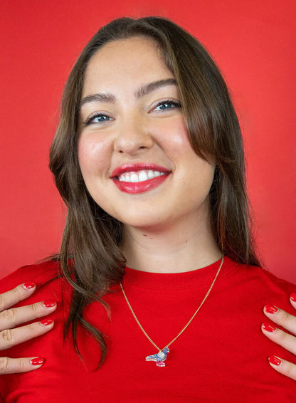 Smiling woman in a red top wearing the pigeon pendant