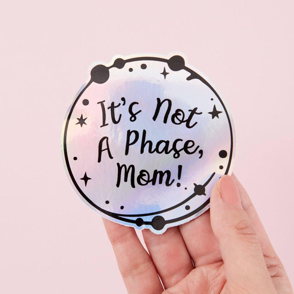 Punky Pins holographic sticker reading 'It's not a phase, Mom!', held in a hand
