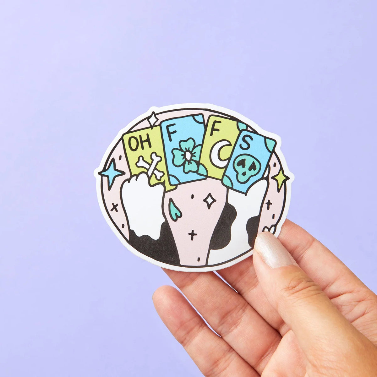 Hand holding a cat paw sticker with tarot-style cards spelling OH FFS