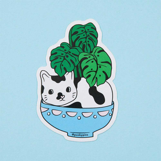 Sticker of a cat sitting in a blue bowl with a monstera plant