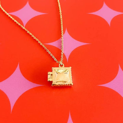 Gold ravioli locket necklace on a red and pink background
