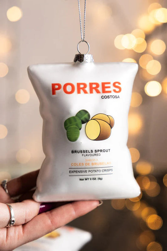 Glass Christmas decoration shaped like a white bag of Porres Brussels sprout crisps, held in a hand