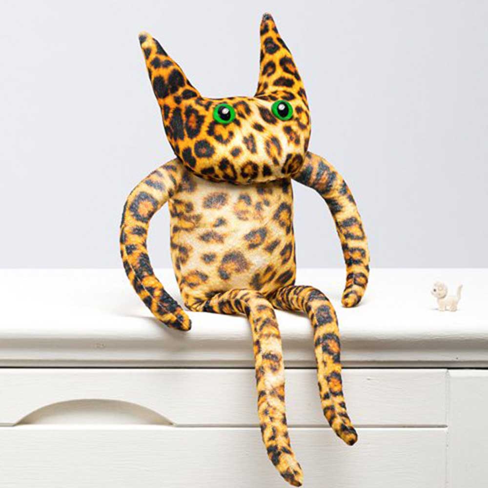 Large leopard print cat soft toy with long legs and green eyes, sitting on a shelf