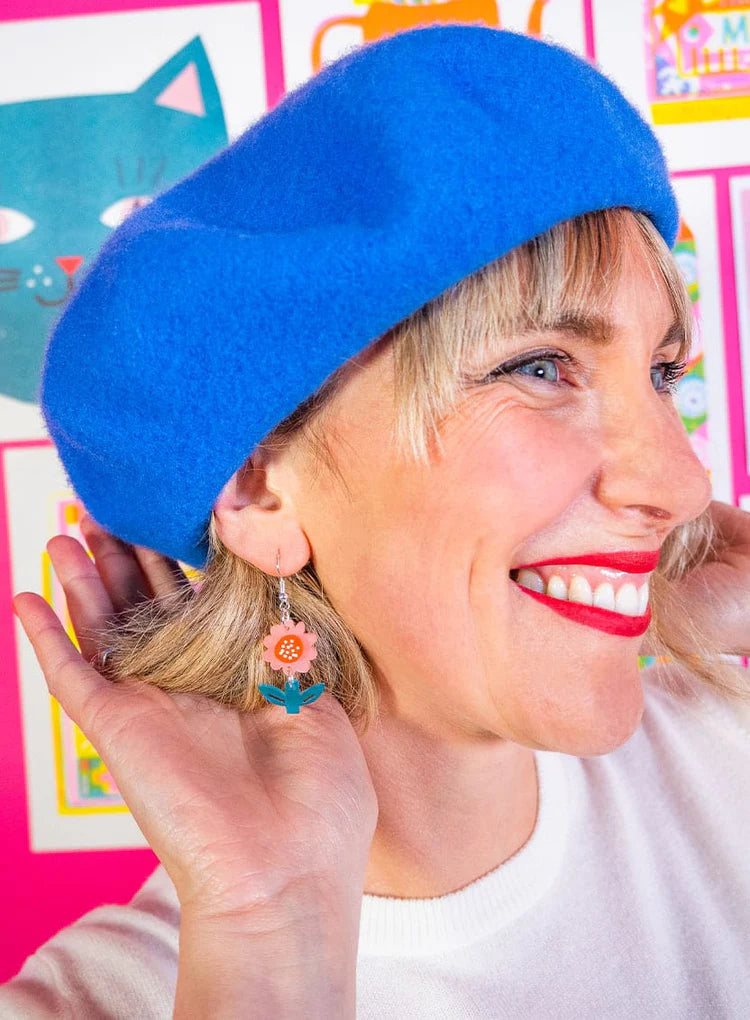 Woman in a blue beret wearing the flower earrings
